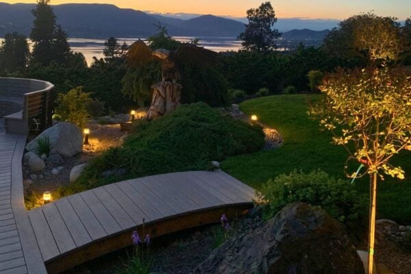 Custom outdoor uplighting showcasing trees and stone textures in a luxury Kelowna yard