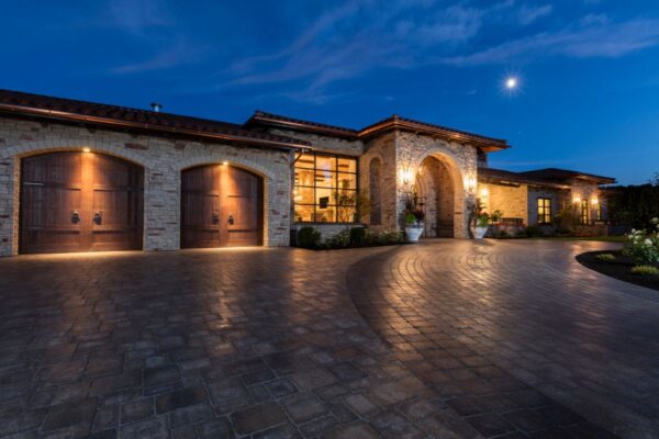 Kelowna luxury home with curb appeal enhanced by nighttime landscape lighting